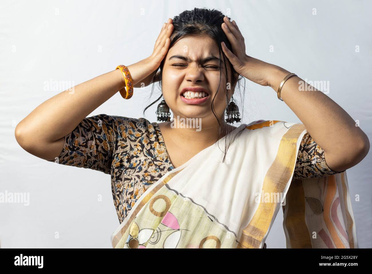 Isolated on white background an Indian woman in saree holding head for headache; sign of migraine Stock Photo
