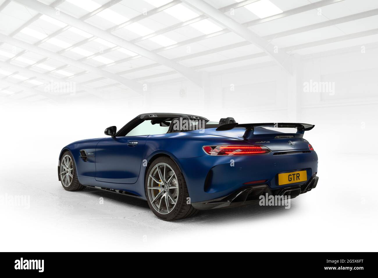 Rear quarter view of a blue 2021 Mercedes AMG GTR V8 Biturbo with the top down - Stock Image