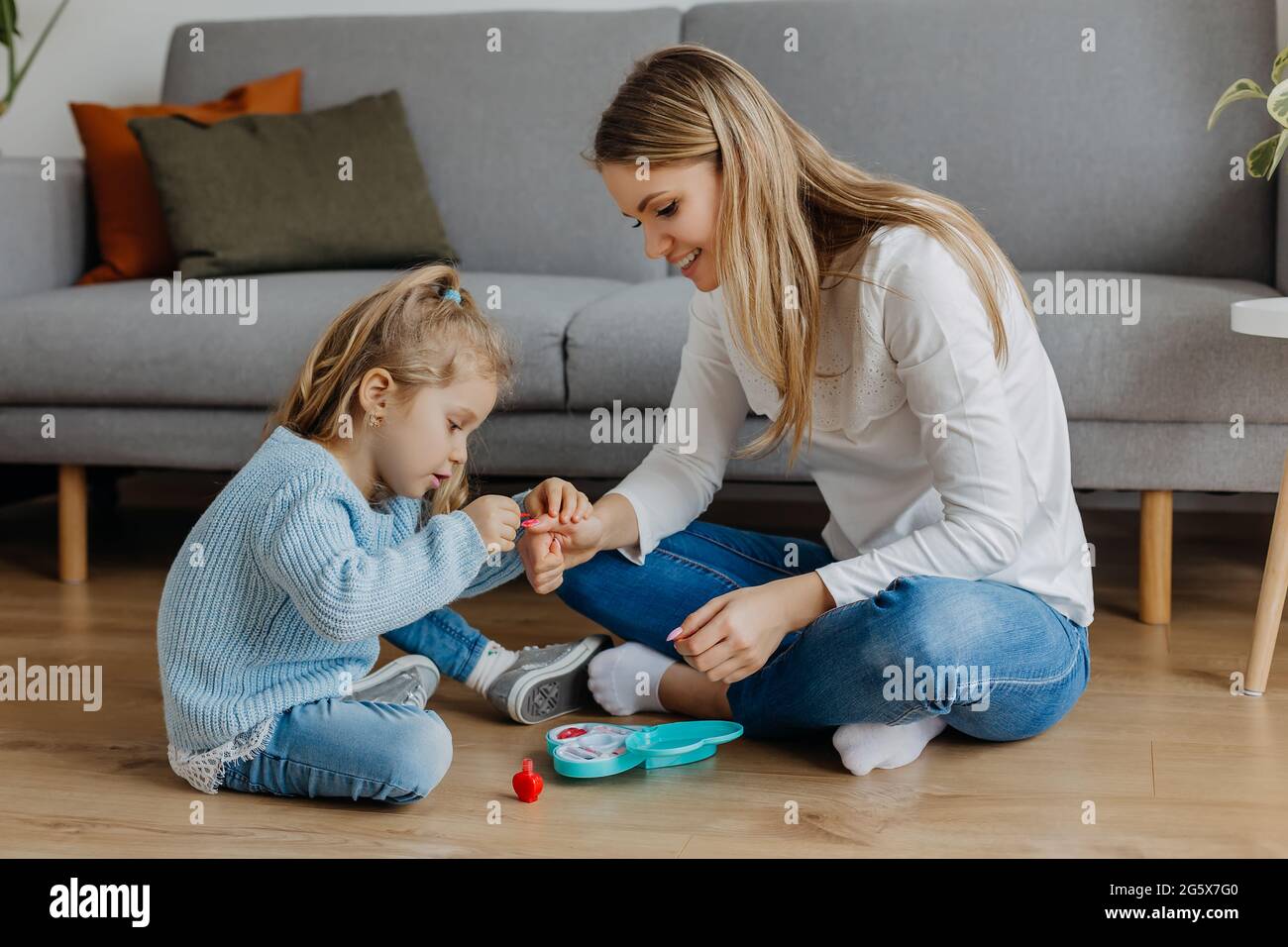 Mother and little daughter paint their nails with toy nail polish. Kid