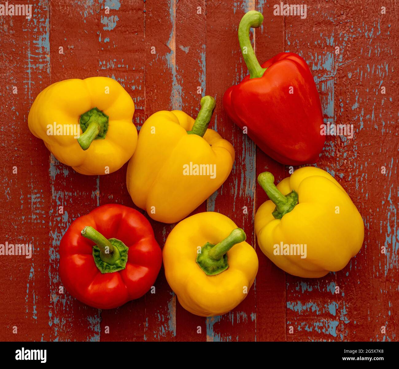 Plan view of red and yellow bell peppers on a brown and blue  wooden background. Stock Photo