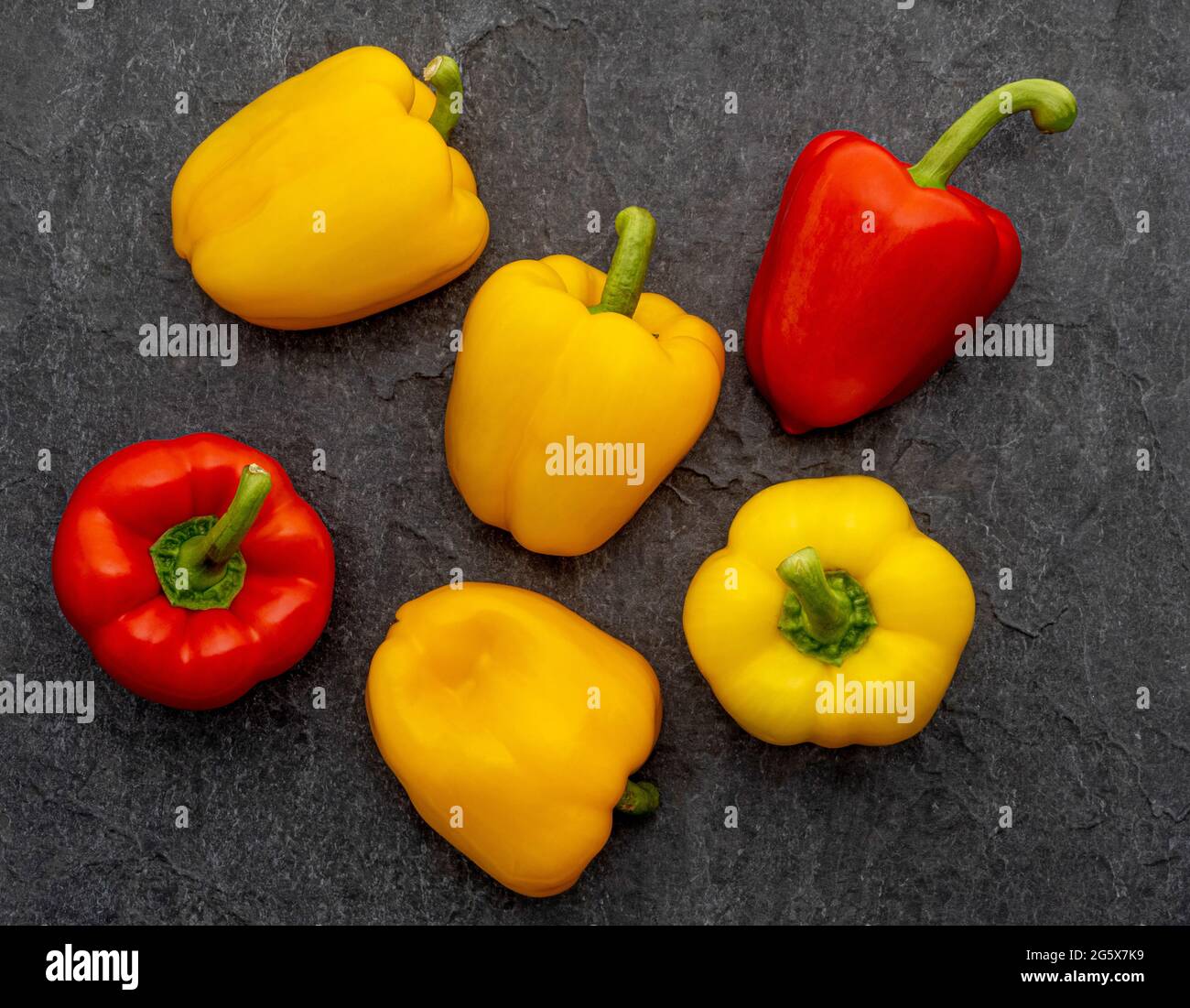 Plan view of red and yellow bell peppers on a grey textured background. Stock Photo