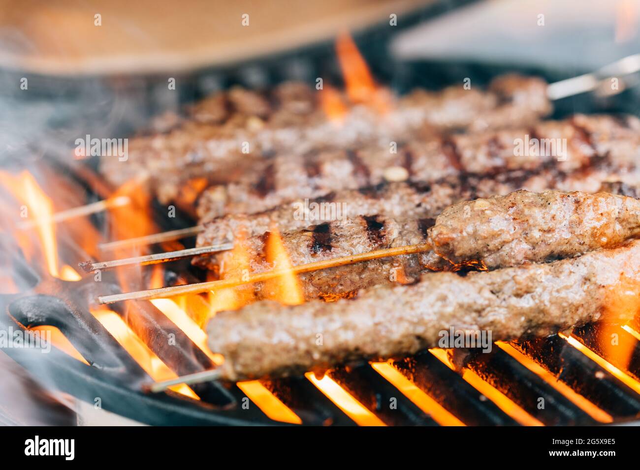 Lambs kebab on a ceramic barbecue with fire. Cast iron grill. Closeup