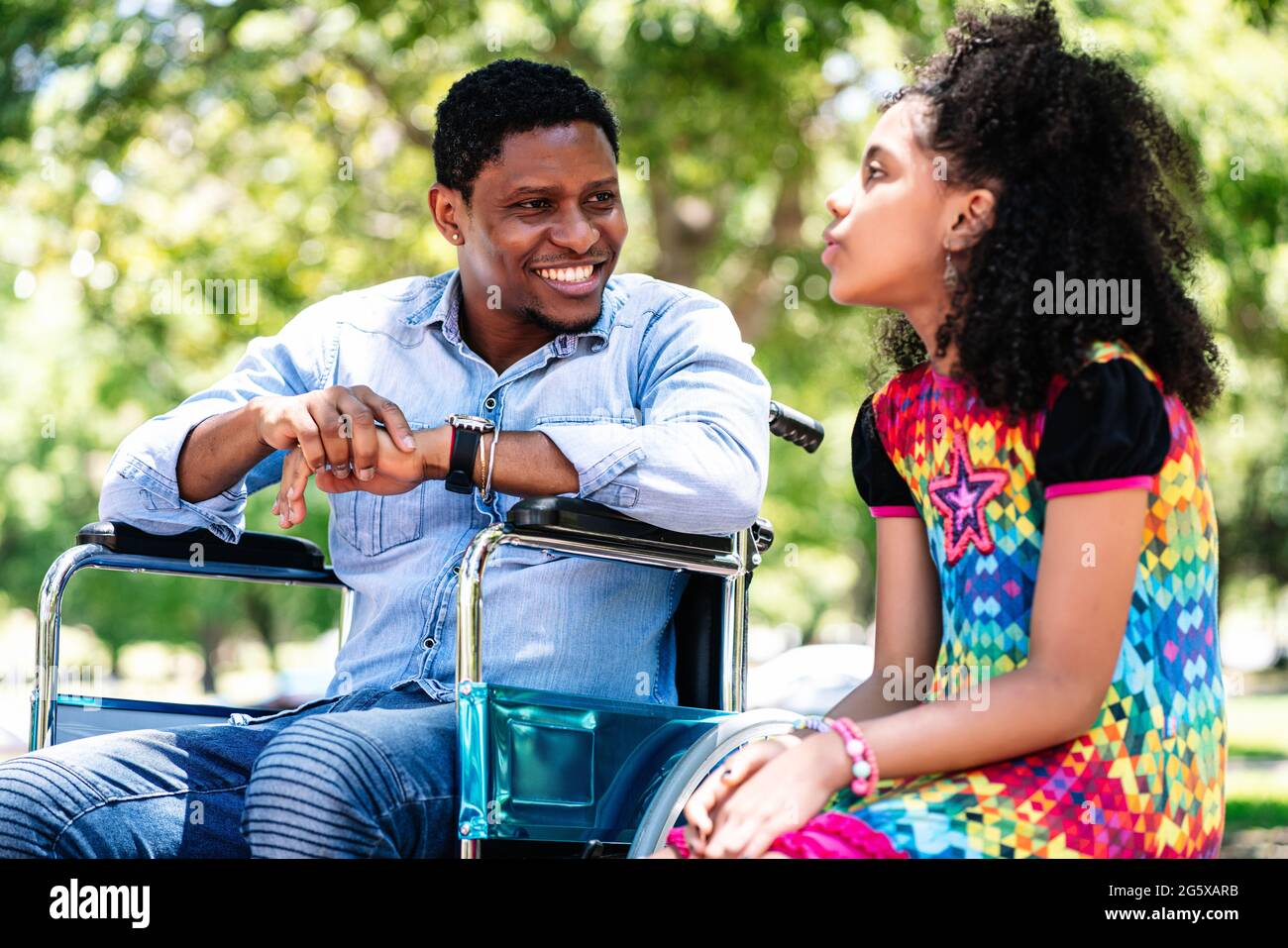 Man in a wheelchair at the park with his daughter Stock Photo - Alamy