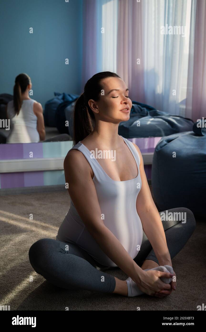Happy pregnant woman practice yoga. A girl in the third trimester leads Pilates. Classes to prepare for childbirth. Waiting for the baby. Appeasement. Stock Photo
