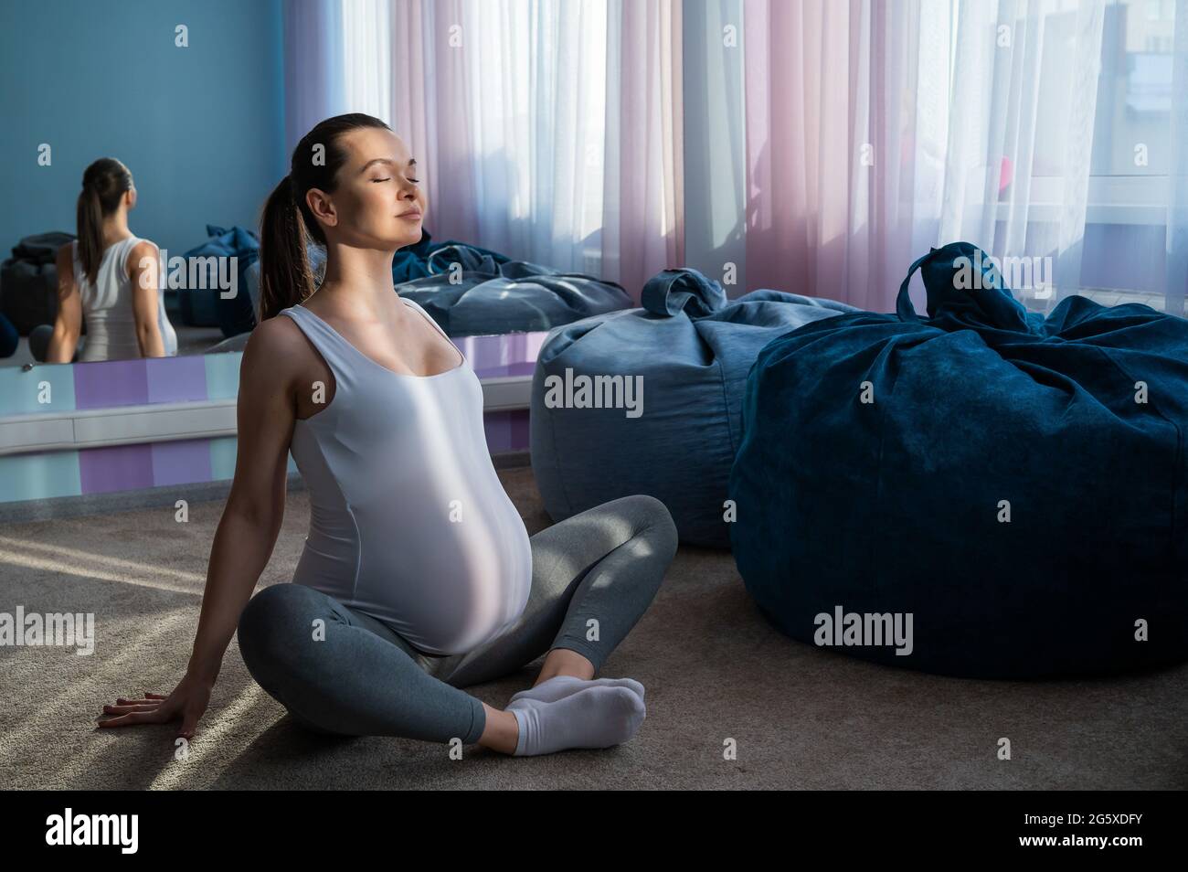 Happy pregnant woman practice yoga. A girl in the third trimester leads Pilates. Classes to prepare for childbirth. Waiting for the baby. Appeasement. Stock Photo