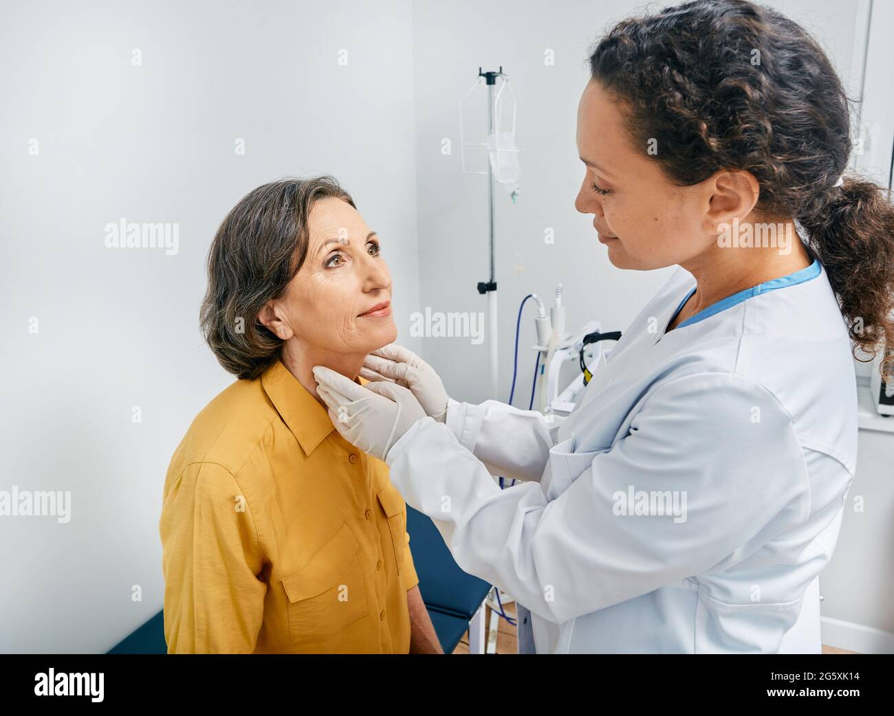 doctor palpates of fat mature woman's neck for diagnostics of thyroid diseases and hypothyroidism at medical clinic. Thyroid treatment Stock Photo