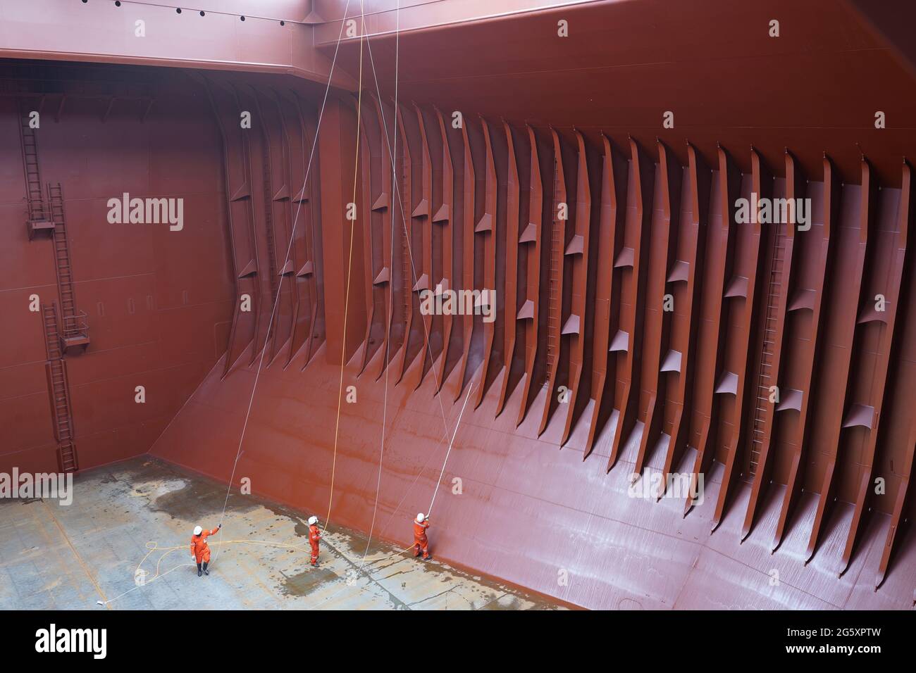 crew preparing cargo hold before loading cement, applying hold block, in the hold of big bulk carrier vessel Stock Photo