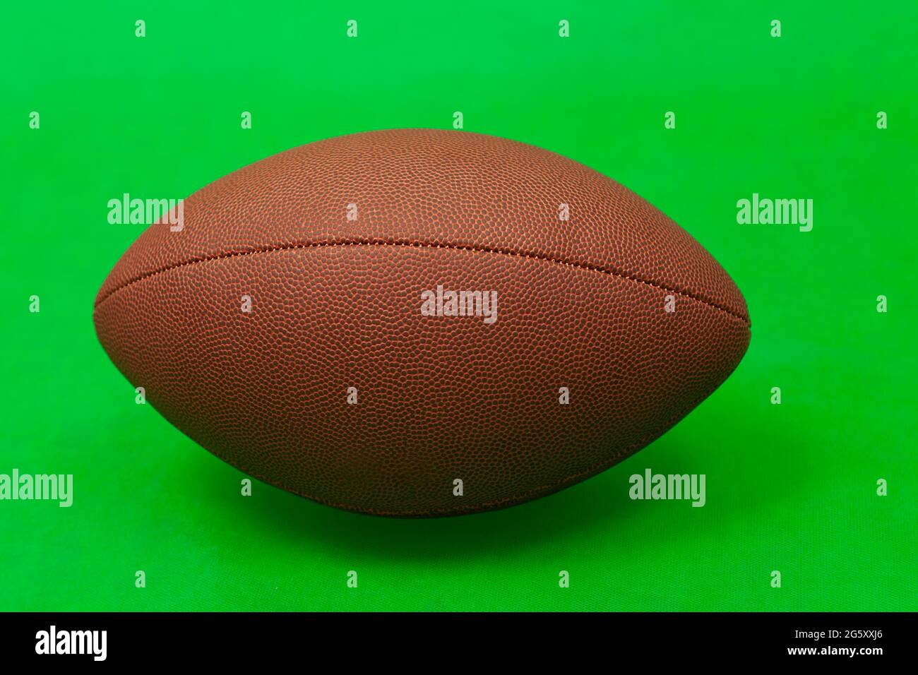 A brown american football ball isolated on a green background Stock Photo