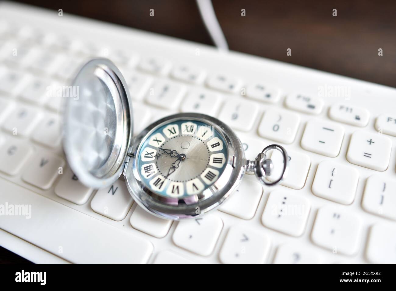 Antique vintage pocket watch lies on a white keyboard. The concept of ...