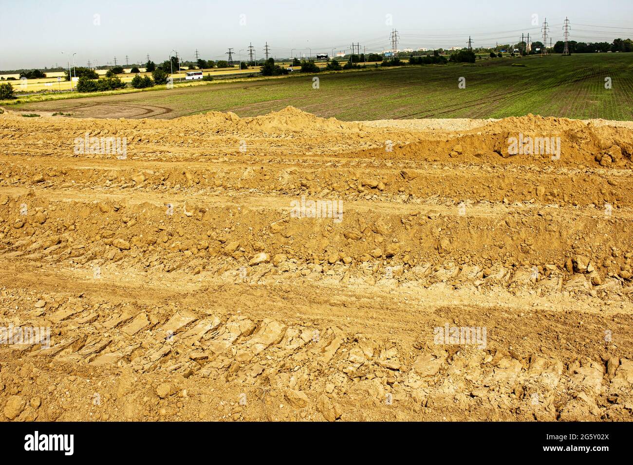 Clay soil after leveling with a bulldozer. Excavator tracks in red mud