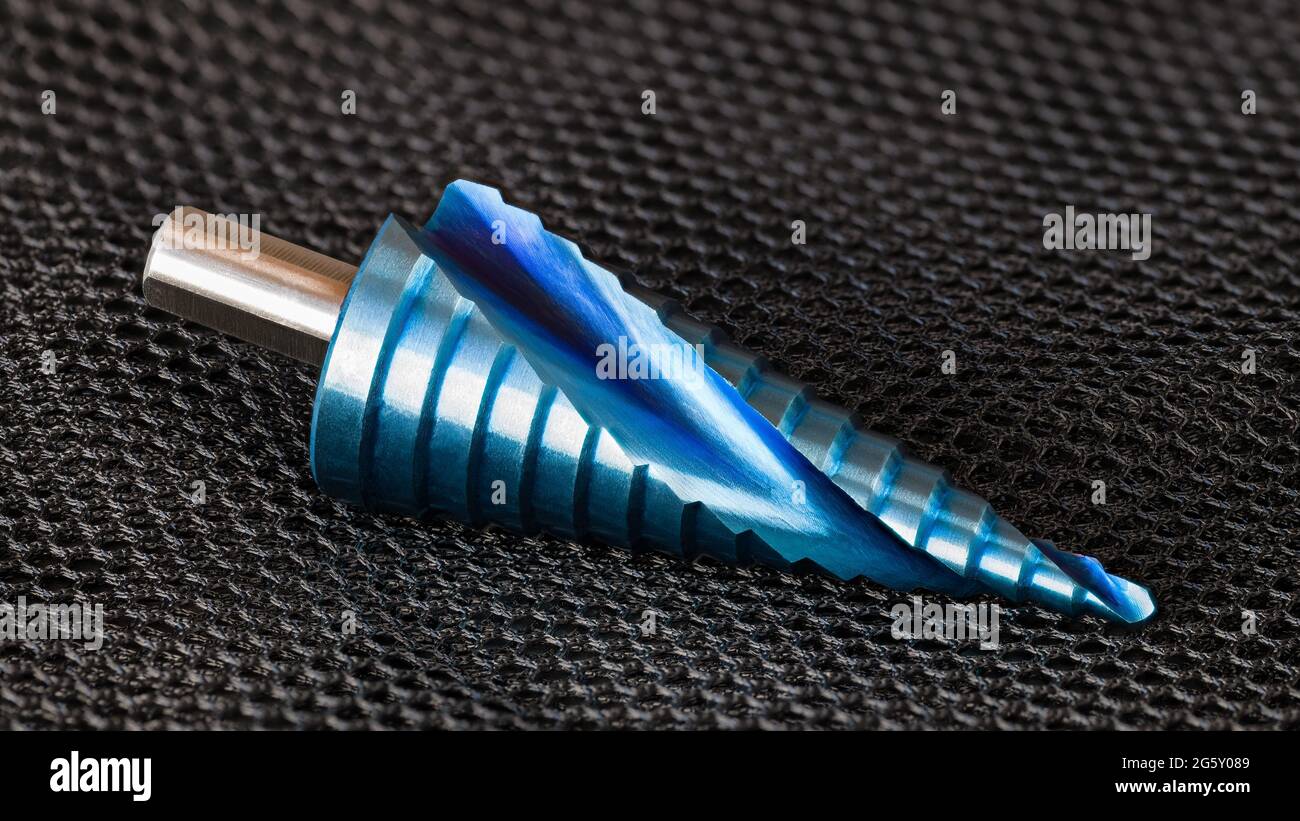 Closeup of conical step drill bit with spiral flute and blue surface finish on net black background. One nano coated unibit to boring varied hole size. Stock Photo