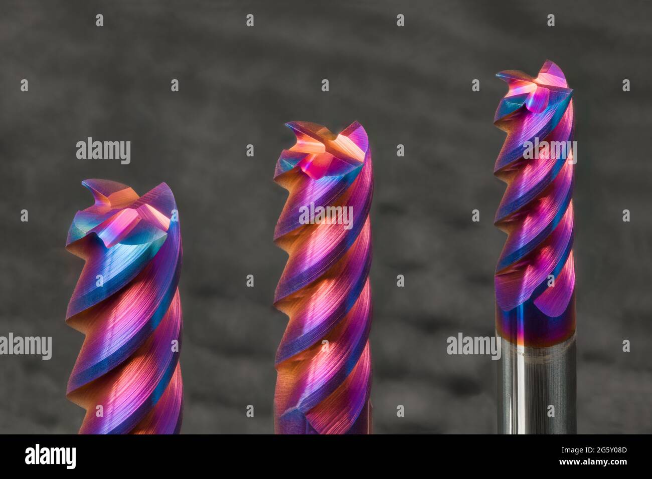 Three steel end mills with beautiful colored nano coating on gray
