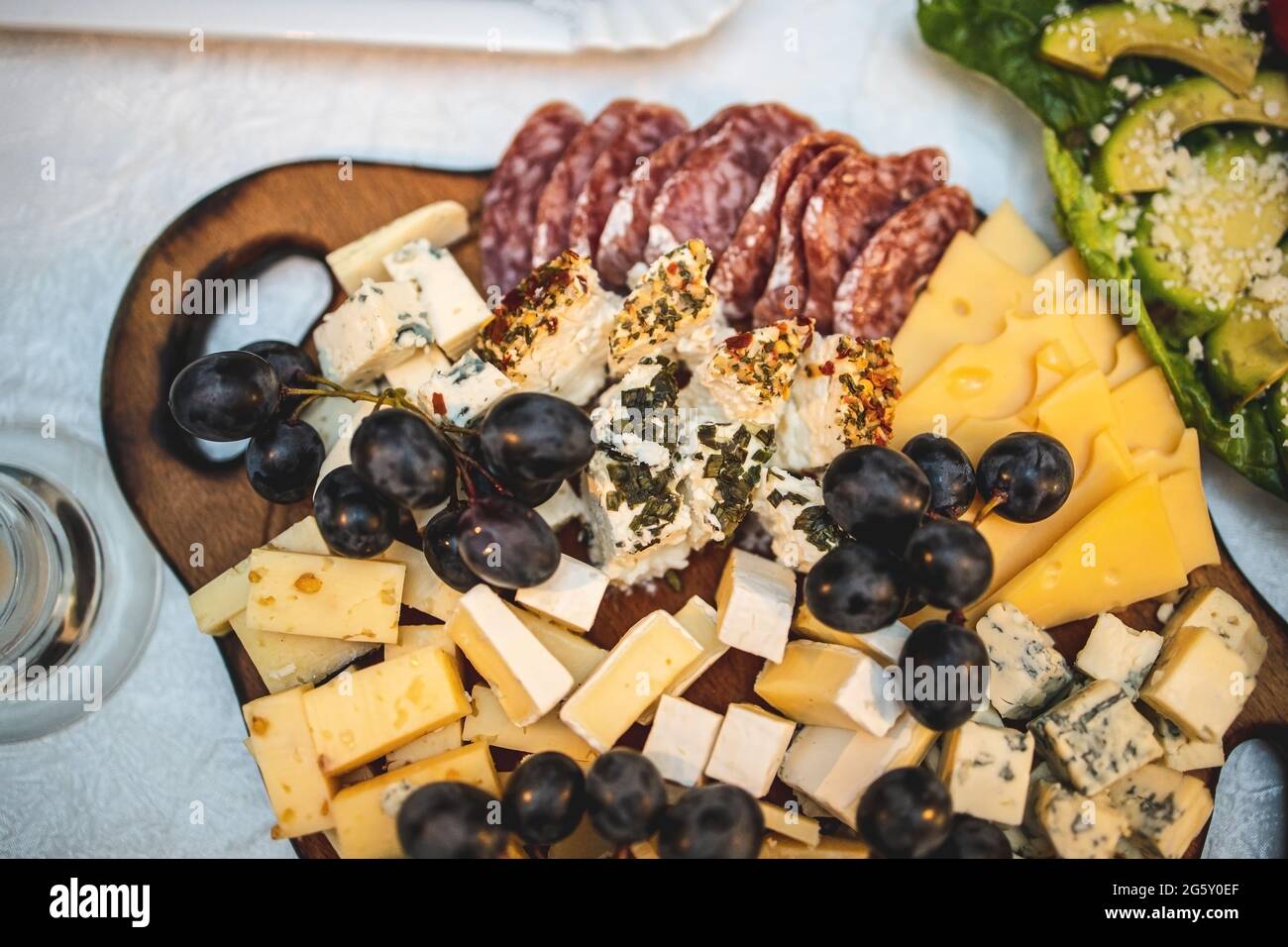 Cheese and meat platter on a wooden board on a festive table. View from above Stock Photo