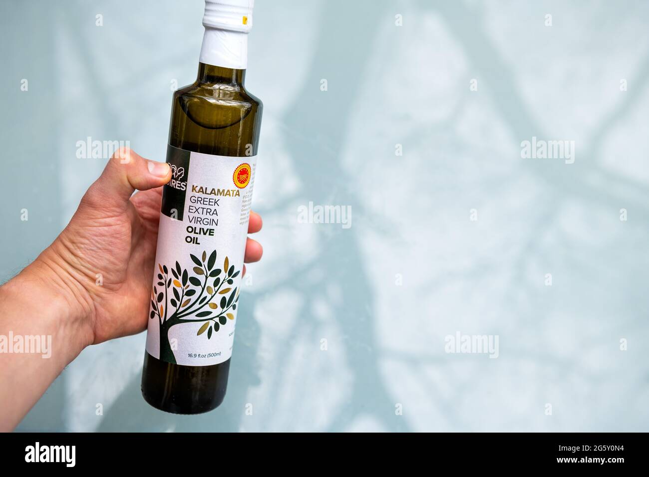 Nellysford, USA - April 29, 2021: Closeup of hand holding Moires PDO Kalamata EVOO Kalamata greek extra virgin olive oil bottle and sign label Stock Photo