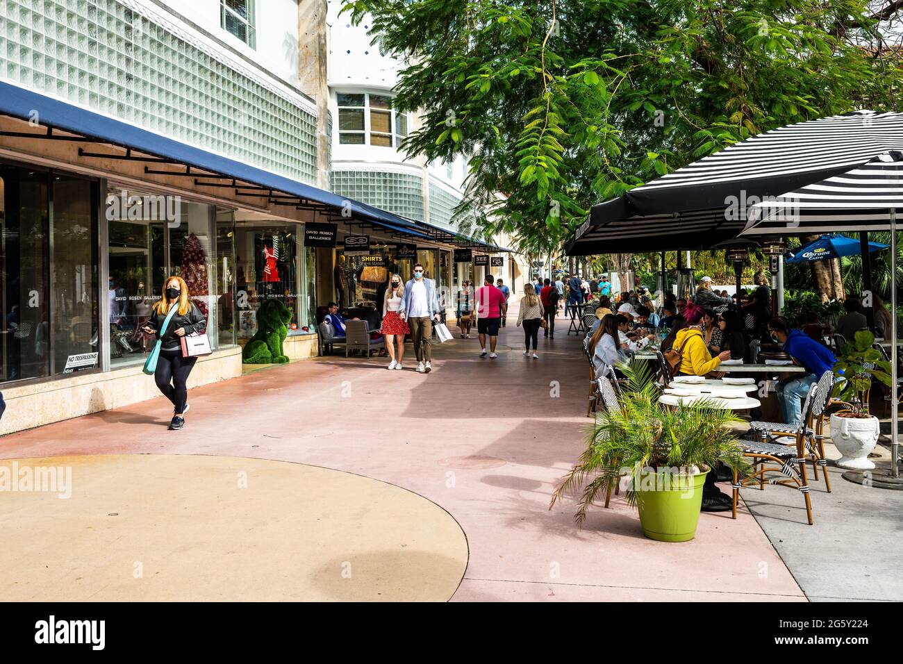Miami Beach, USA - January 17, 2021: Famous Lincoln road shopping street with people walking on sidewalk by restaurant cafe outdoor dining chairs on s Stock Photo