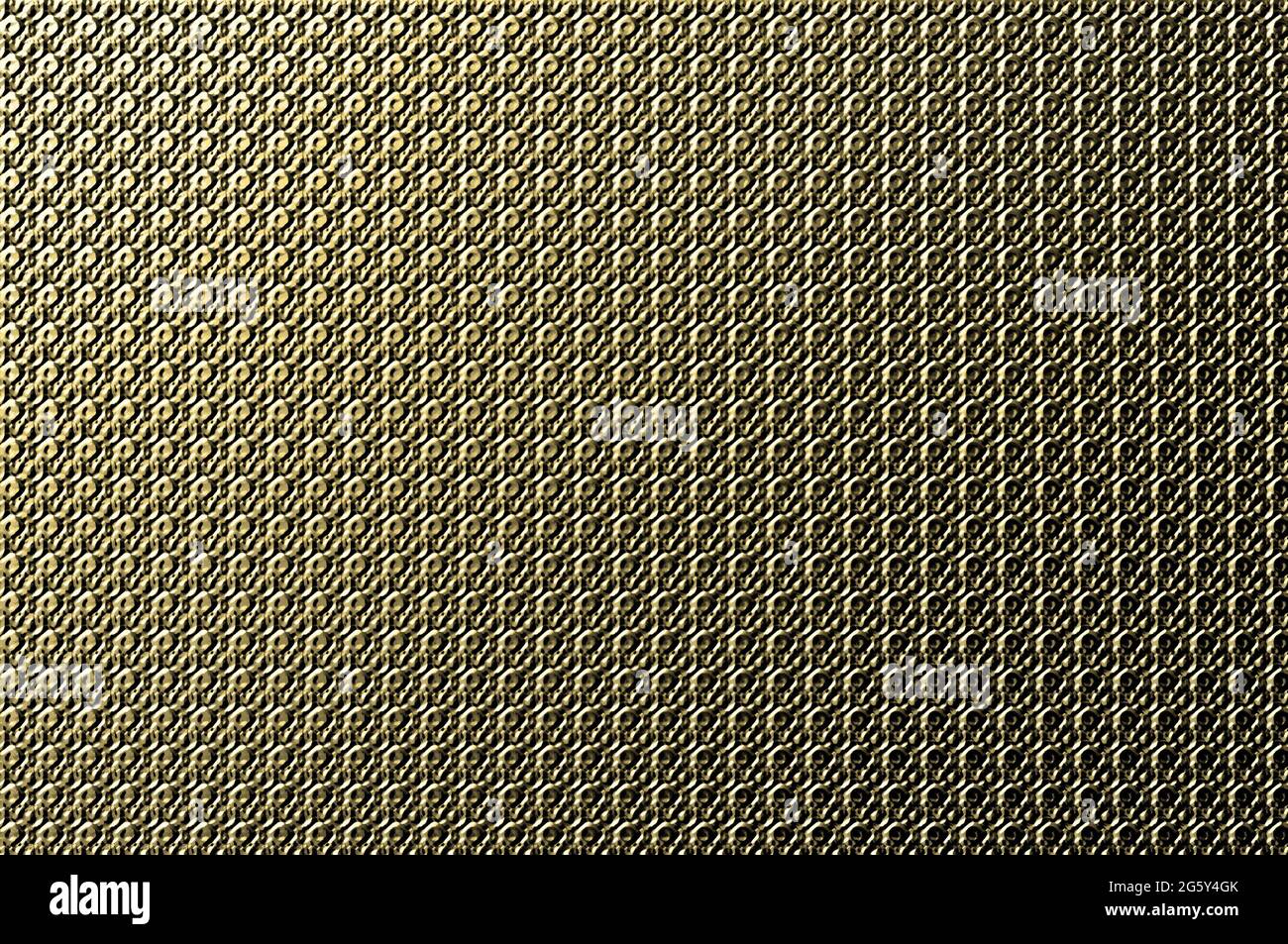 Abstract image of metal plate indented with rows of circles.  Light shines one one end and the other is darker.  Tones of yellow gold. Stock Photo