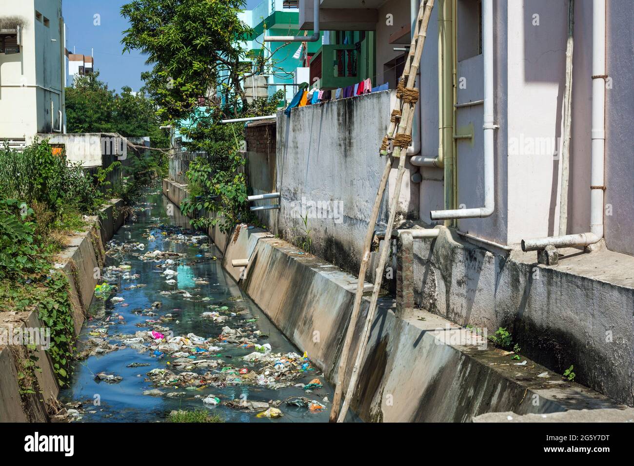Stream beside building using as dumping site littered with garbage