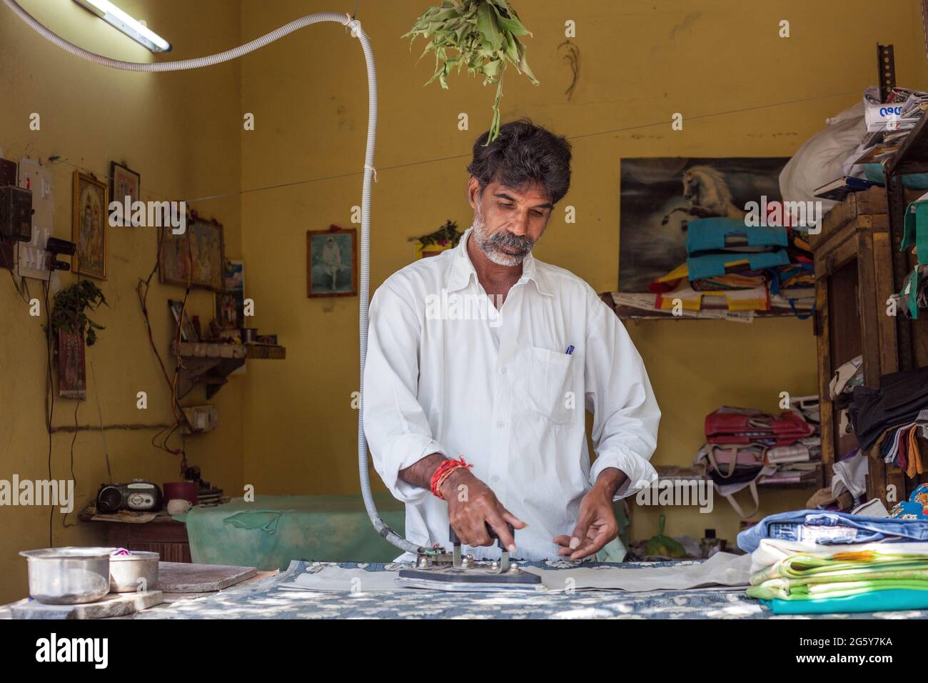 Indian male using traditional old fashioned industrial electric steam iron on garments, Puducherry (Pondicherry), Tamil Nadu, India Stock Photo