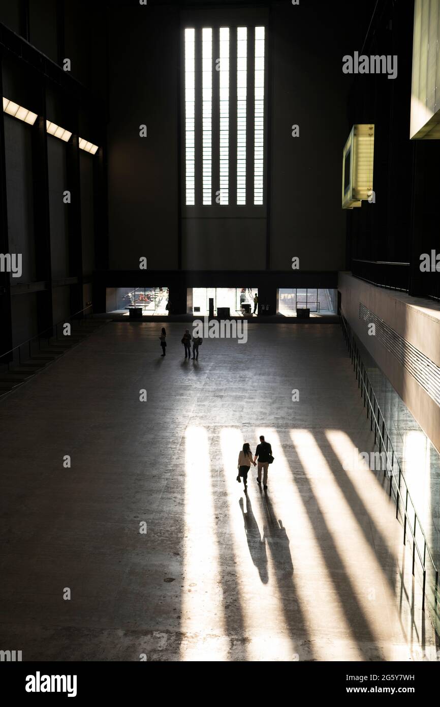 A couple walking through a shaft of light in The Tate Modern in London, UK Stock Photo
