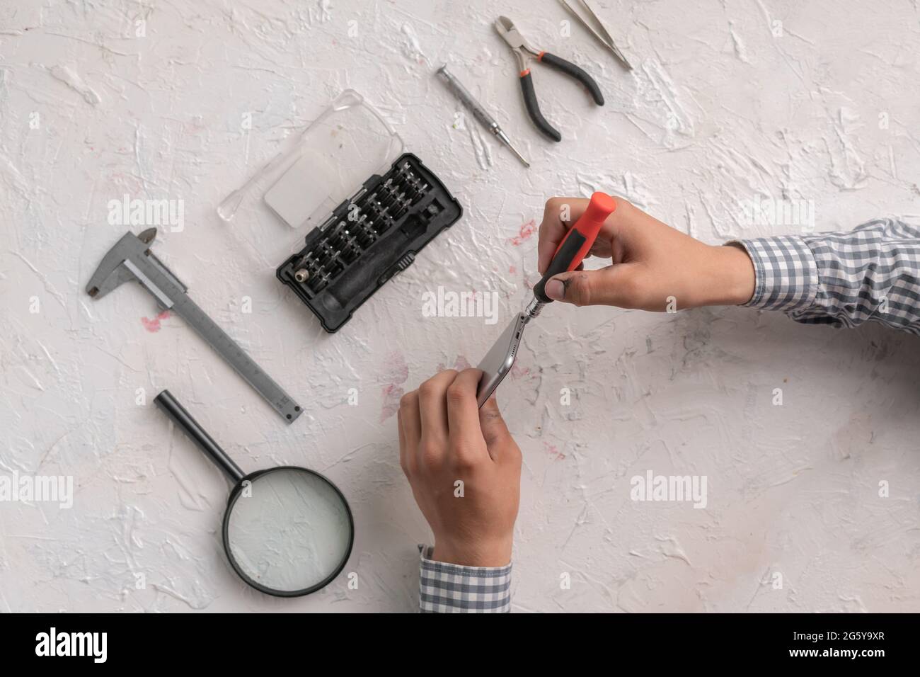 master with tools repair the broken smartphone in the workshop Stock Photo