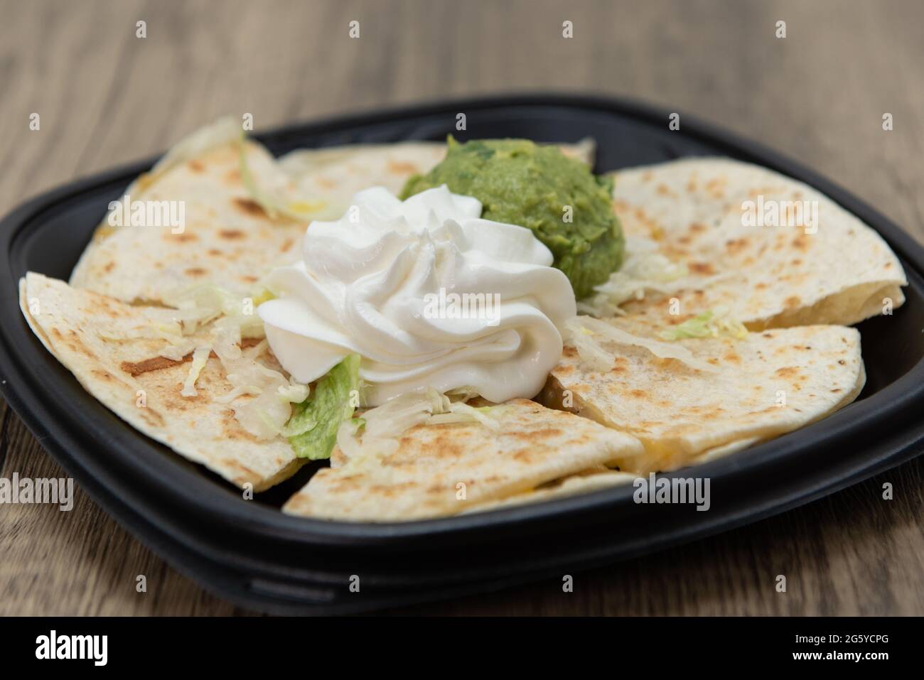 Artistic mound of white sour cream garnishes the tortilla quesadilla meal. Stock Photo