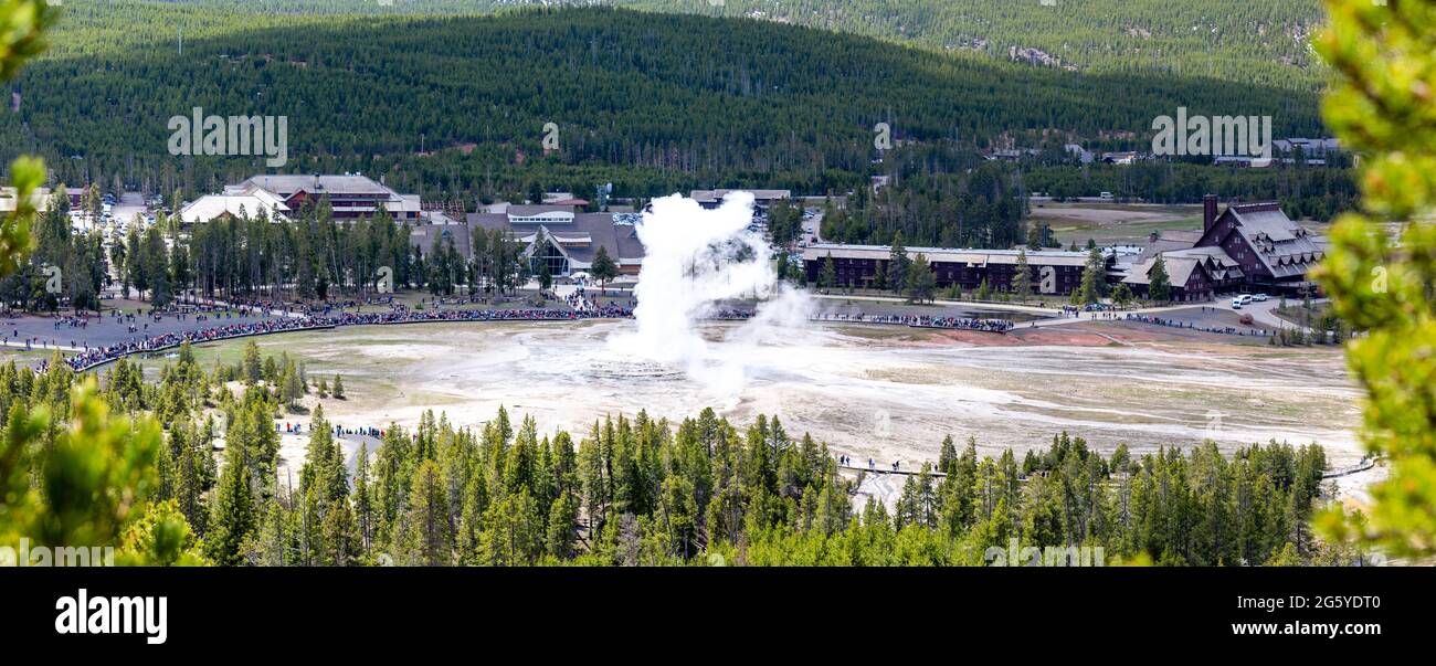 Yellowstone, Wyoming, USA, May, 25, 2021,  tourists in the Upper Geyser Basin watching Old Faithful erupt, panorama Stock Photo