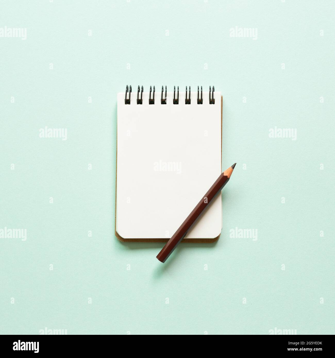 Blank notebook and colored pencil on blue background. top view, copy space Stock Photo