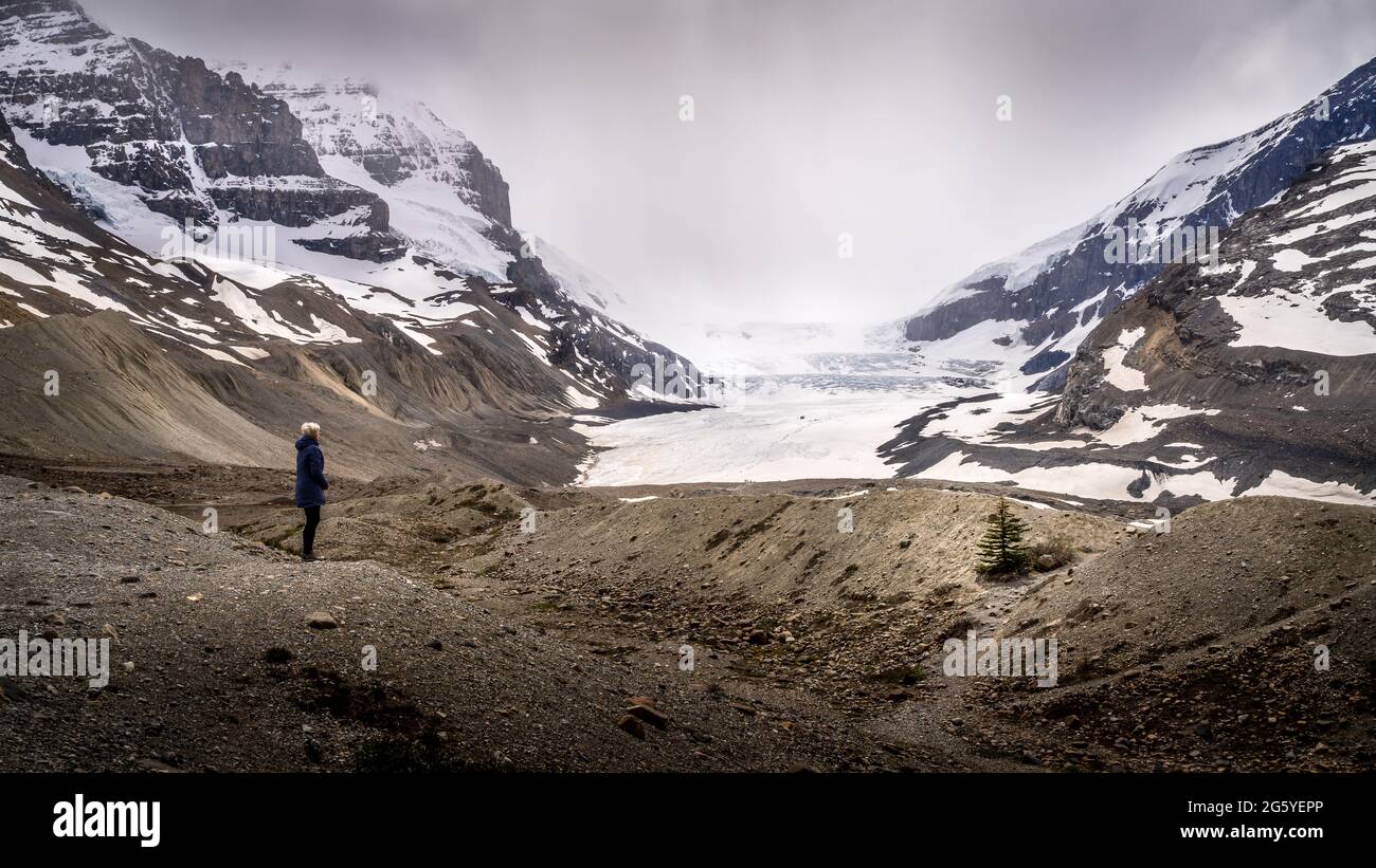 Woman looking at the Cloud Cover over the Athabasca Glacier of the Columbia Icefields of the Canadian Rocky Mountains in Jasper National Park, Alberta Stock Photo