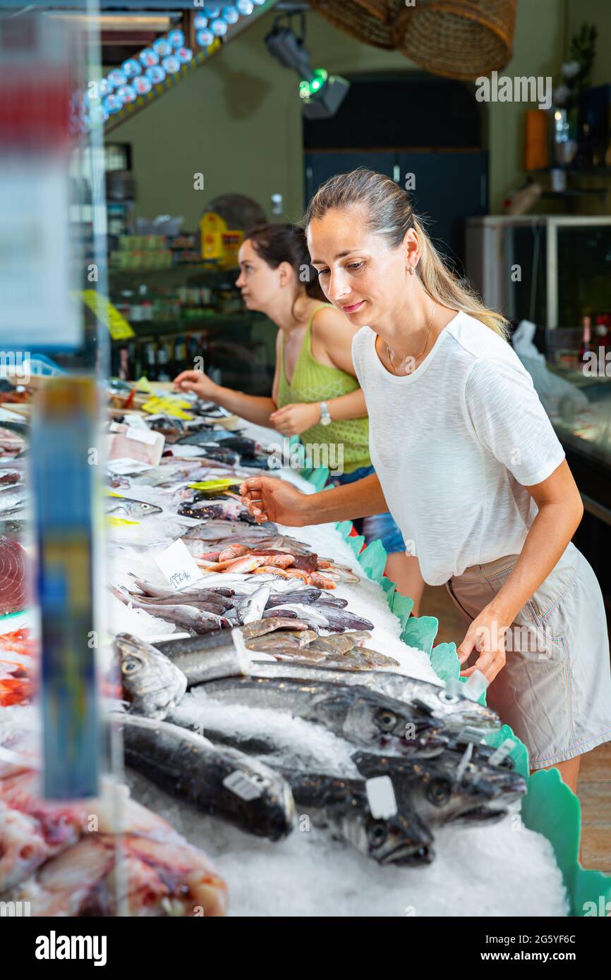 Women looking for fresh marine products on icy showcase of seafood market Stock Photo