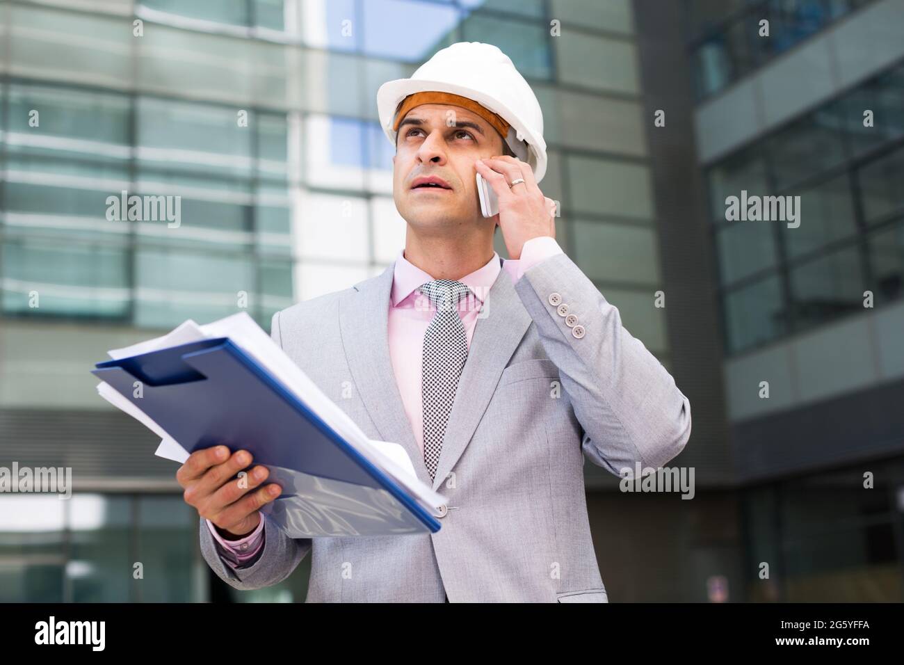 Businessman with papers talking on phone Stock Photo