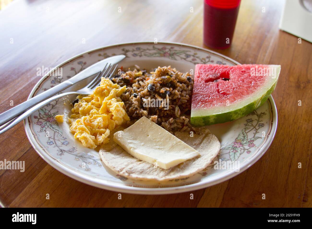 A breakfast of gallo pinto, eggs, cheese, tortilla, and fruit. Stock Photo