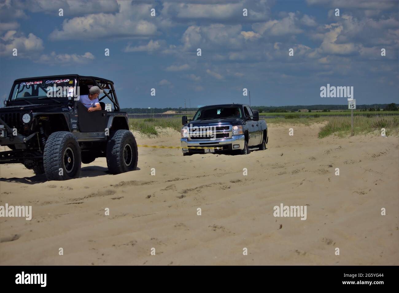 A jeep pulling a Chevy pick-up out of the sand at Carolina Beach, NC Stock Photo