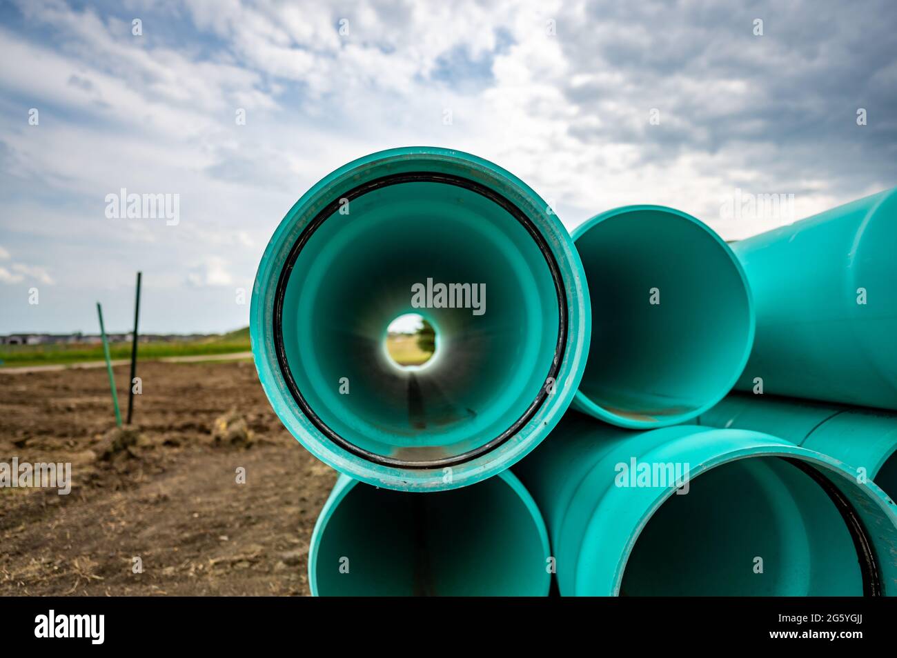 Stacked water main pipe with bell fitting next to an exposed trench for