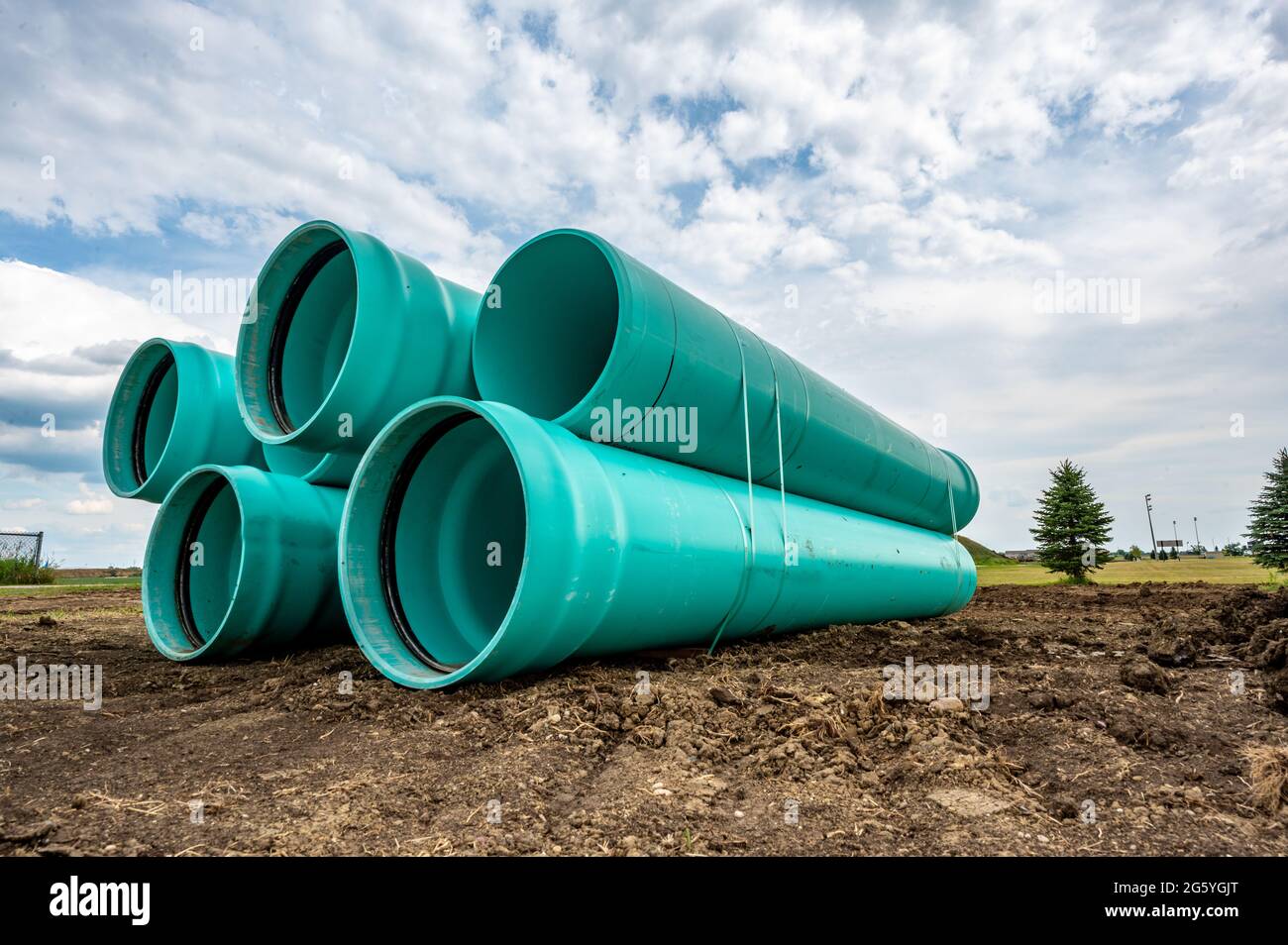 Stacked water main pipe with bell fitting next to an exposed trench for