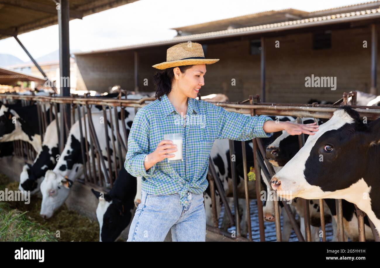 Portrait of a positive kazakh farmer woman in a cowshed, holding a ...