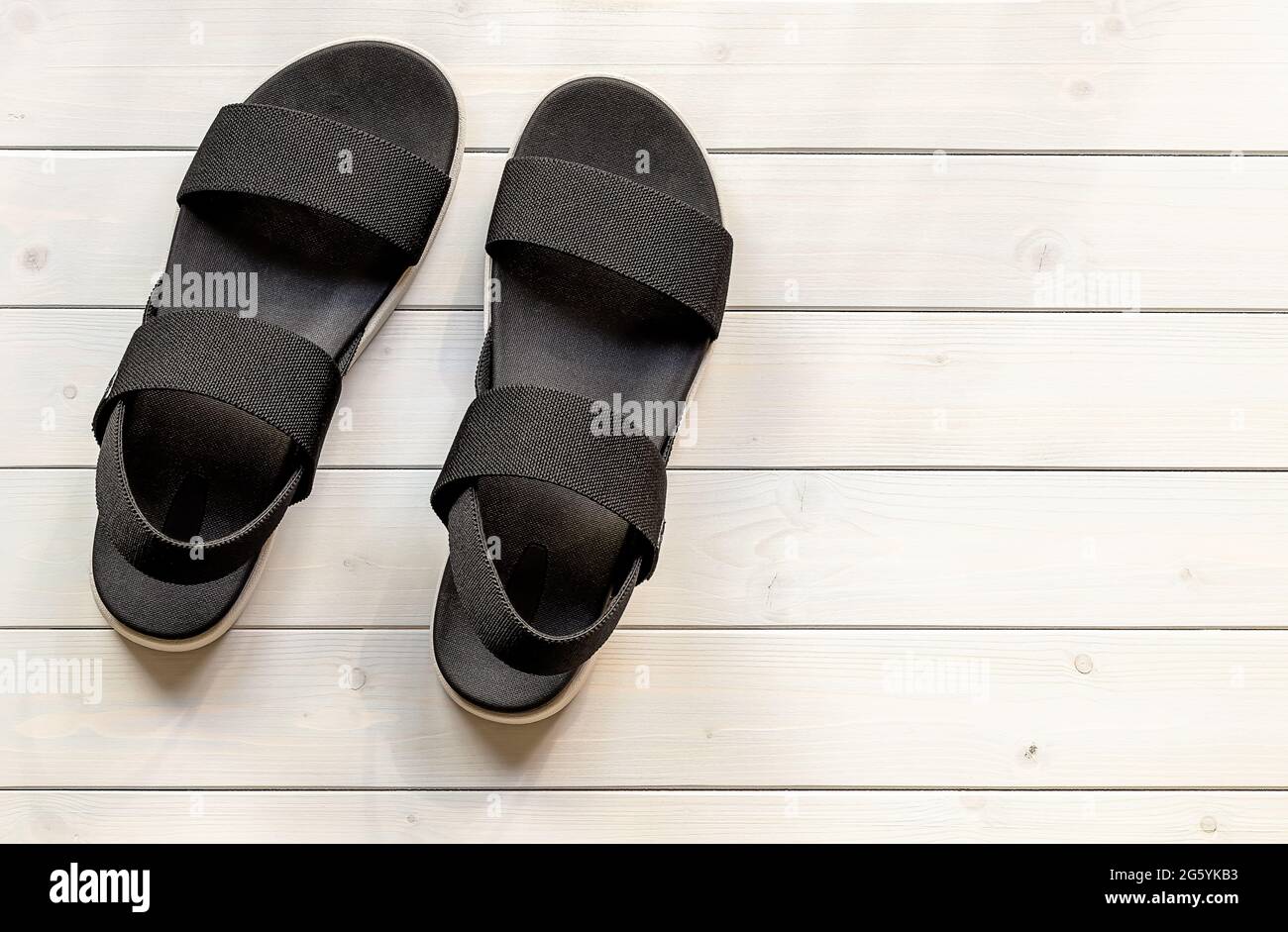 Women's casual platform open-toe black sandals from eco recycled plastic fibers on the white wooden background. Stock Photo