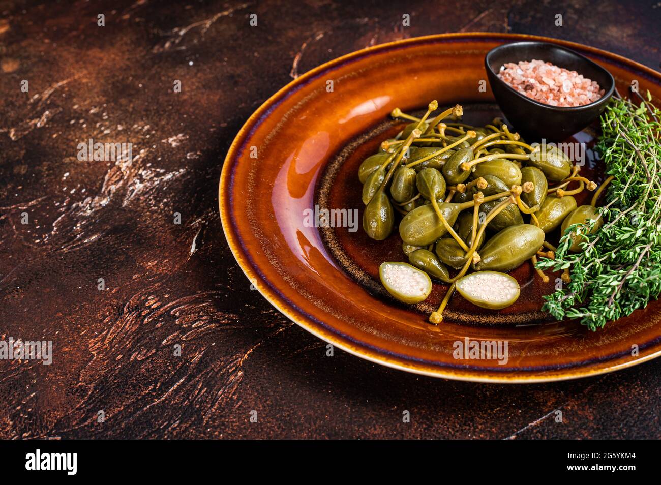 Marinated canned Capers berries in a rustic plate. Dark background. Top ...