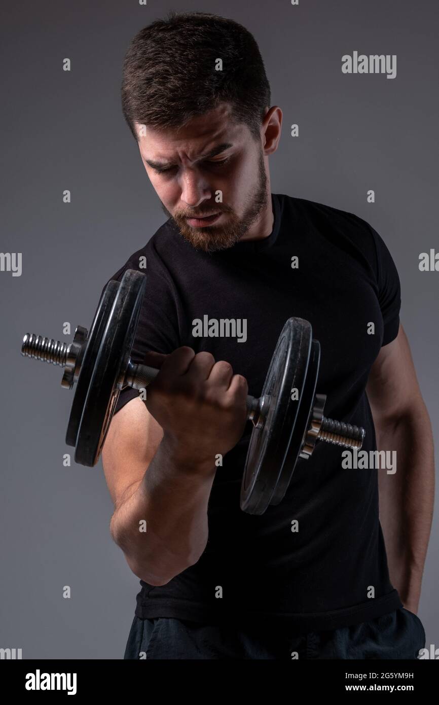 Concentrated young man performing bicep curl with dumbbell Stock Photo ...