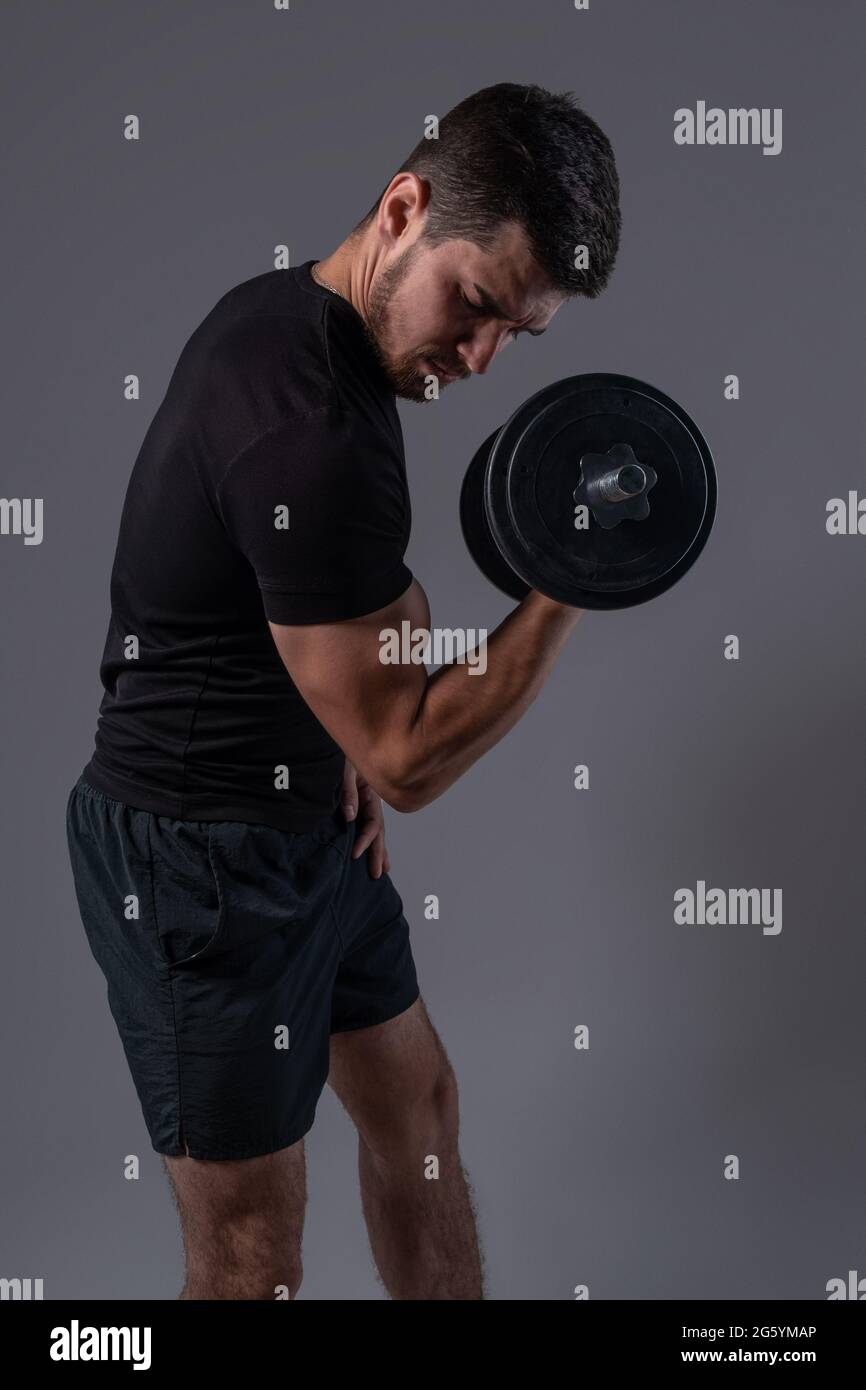Focused young man performing dumbbell bicep curl Stock Photo - Alamy