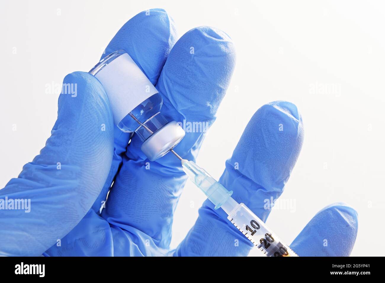 Close-up of hand in gloves holding an unmarked vial and extracting fluid to syringe for injection. Healthcare, medicine, pharmacy and vaccination conc Stock Photo