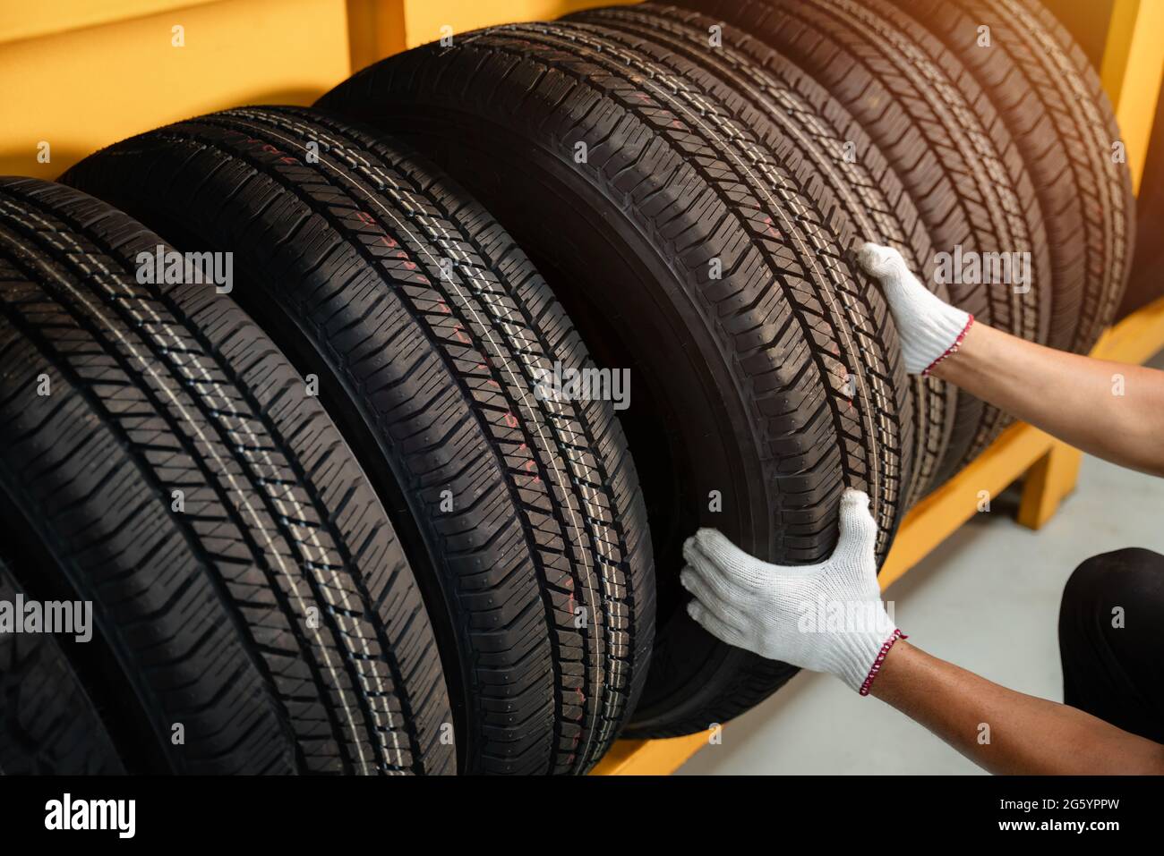 Close to the hands of a tire changer in Large warehouse of car tires ...