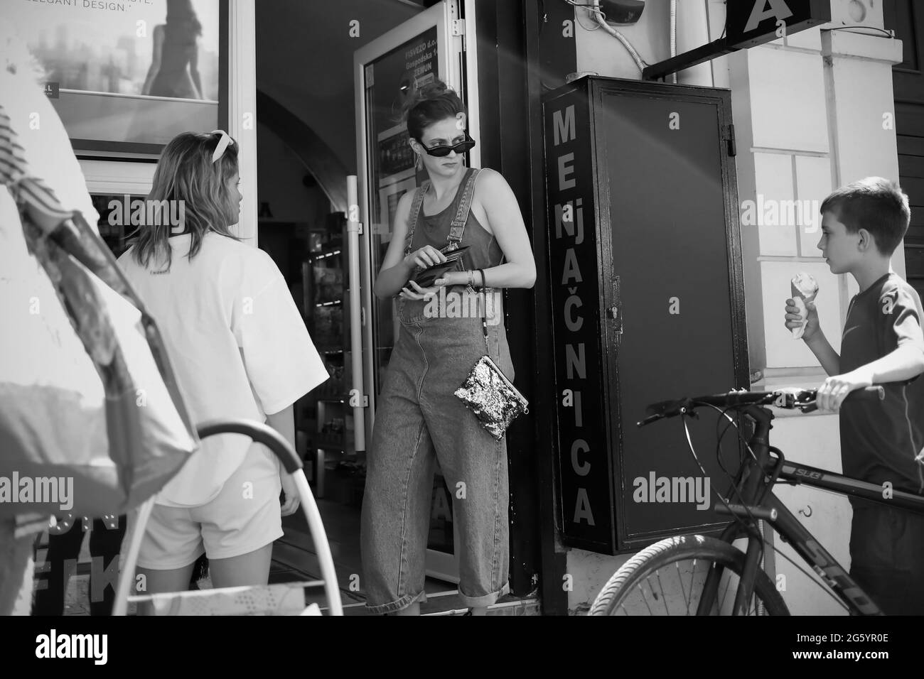 Belgrade, Serbia, May 23, 2021: Young woman waiting in a line in front of the store looks behind over sunglasses (B/W) Stock Photo