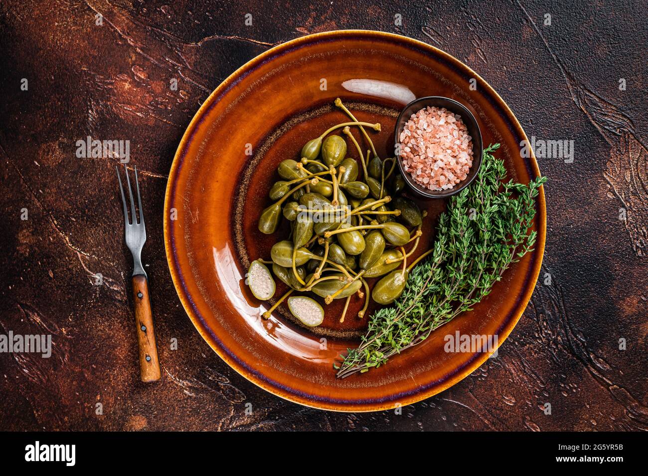 Marinated canned Capers berries in a rustic plate. Dark background. Top ...