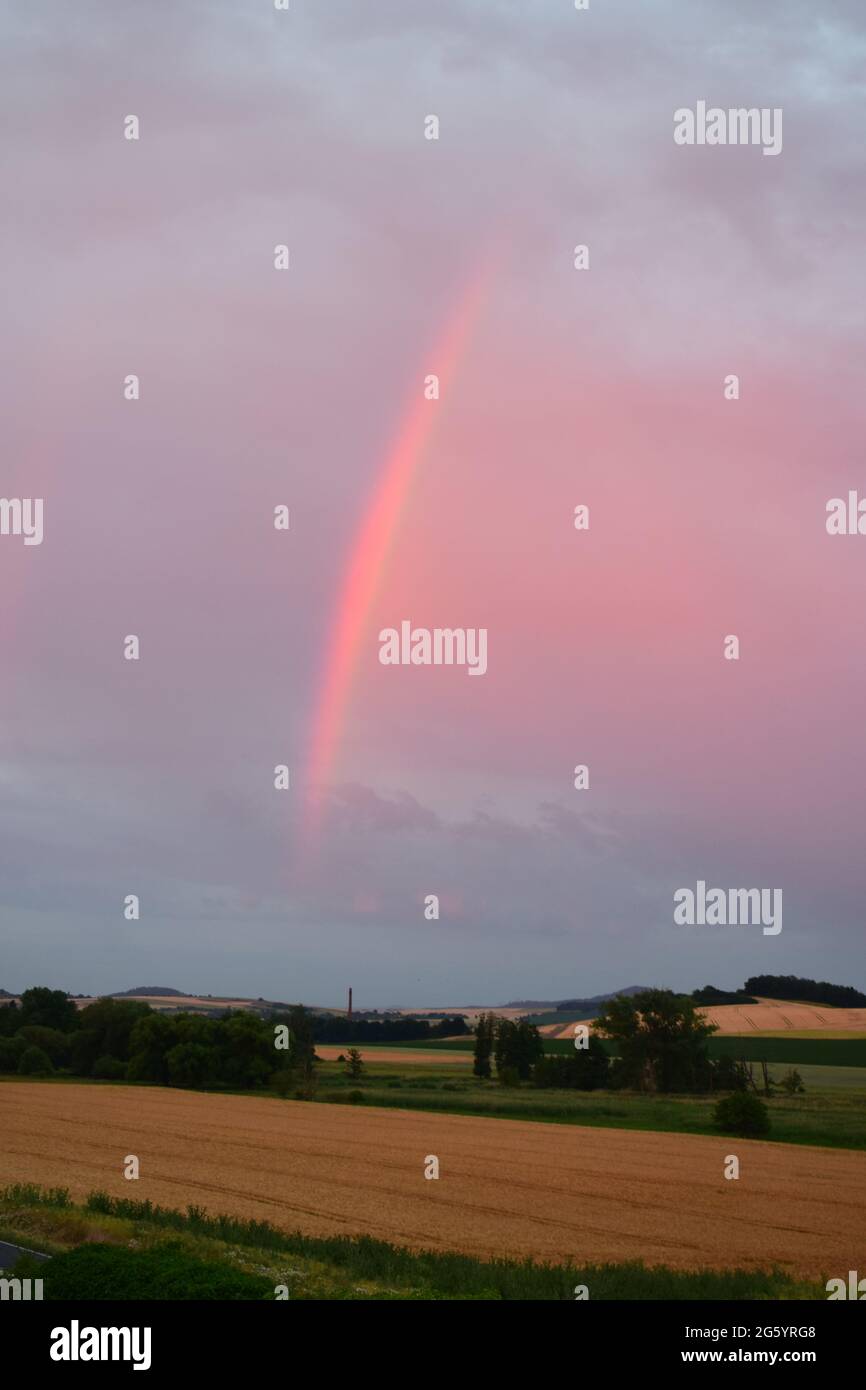 rainbow in red dusk clouds Stock Photo