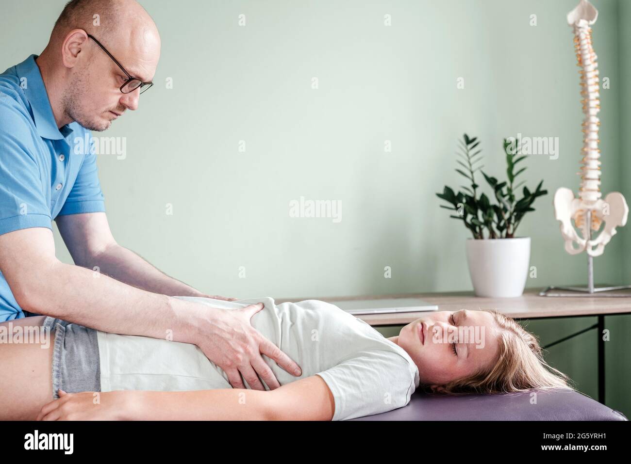 Osteopath practitioner releasing the diaphragm of a female patient, rib
