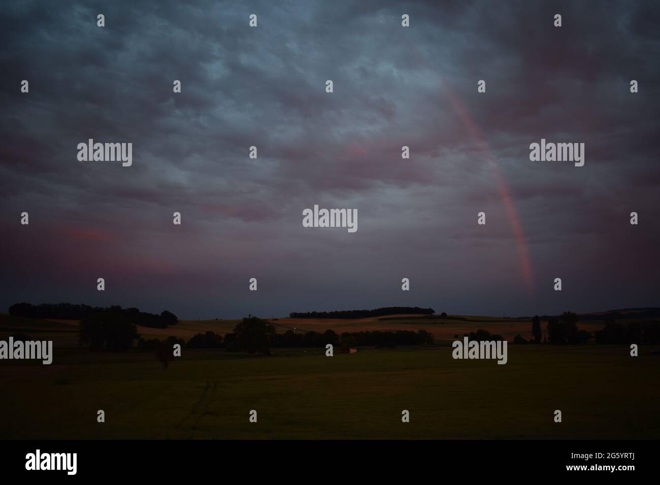 rainbow in red dusk clouds Stock Photo