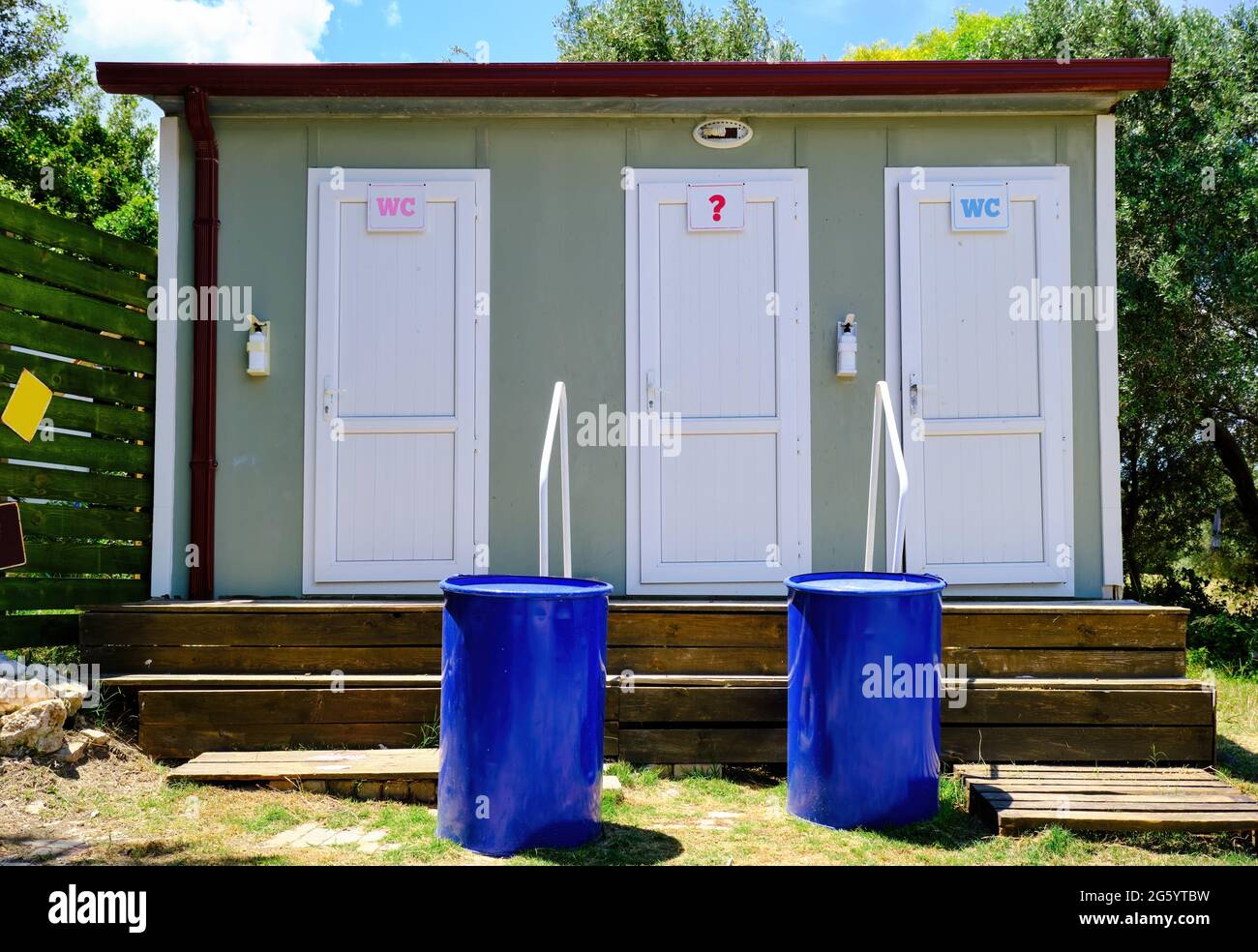 Prefabricated portable toilet cabin exterior with three doors for men, women and a question mark for various gender identity. Stock Photo