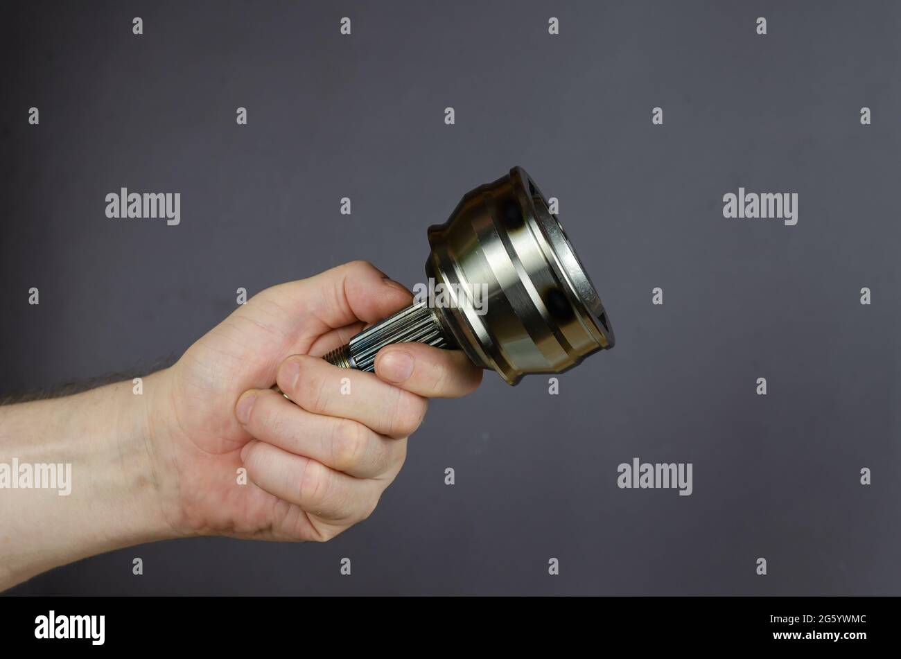 A man demonstrates a Drive shaft joint against a gray background. New