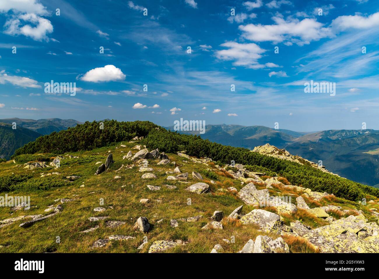 Amazing view from Varful Zlata hill summit above Zanoaga lake in Retezat mountains in Romania with many hills and blue sky with clouds Stock Photo