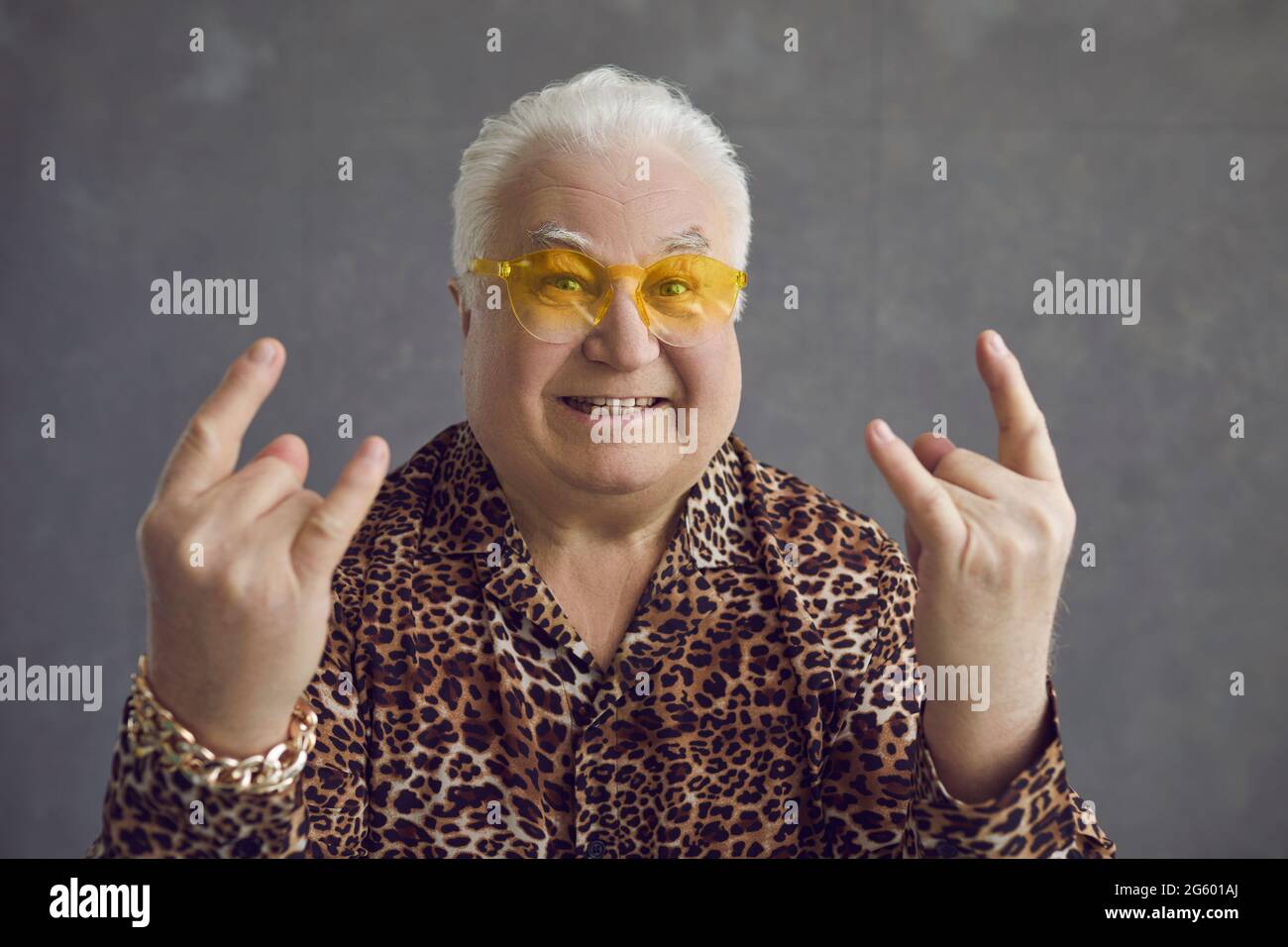 Portrait of happy rich senior man in sunglasses and leopard shirt doing Horn gesture Stock Photo